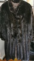 Full view of the long dark brown fur coat showing the overall length, collar, and texture of the fur.