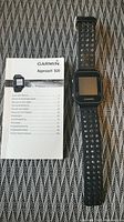 Garmin Approach S20 watch alongside printed user manual on textured surface