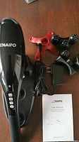 NAIPO cordless handheld percussion massager body, massage heads, power adapter, and user manual on brown surface