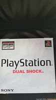 White Sony PlayStation Dual Shock retail box front with branding and console contents image.