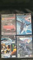 Four PlayStation 2 game cases showing titles Ferrari Challenge, Ace Combat, Need For Speed Underground, and ATV Offroad Fury 4.