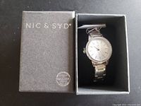 Opened box showing the watch inside its original packaging with Nic & Syd branding and Swarovski authenticity stamp on box lid.