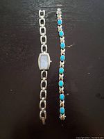 Full view of the silver-tone Eddie Bauer watch with a chain link bracelet alongside a silver bracelet with multiple blue Larimar stones.