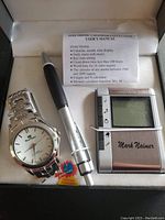 Gift set containing watch, pen, electronic calculator, and user manual inside a box