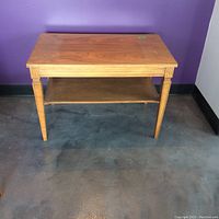 Front-facing image of the wooden coffee table side table showing tapered legs, lower shelf, and rectangular top with wood grain.