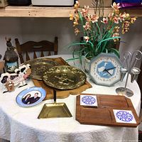 Overview of the household collection items on a round table including plates, flower arrangement, framed photo, decorative items