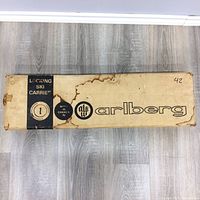Full view of the Carlsberg locking ski carrier packaging box showing brand and product identification with visible water stains and wear on cardboard.