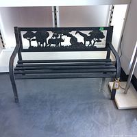 Front view of the black metal bench with silhouette animal motifs on the backrest showing elephants, giraffes, and trees.