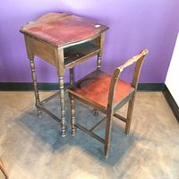 Desk and chair set in wooden construction against purple wall showing front and side profile.