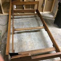 Photo showing the overall bed frame from above, emphasizing the folding top piece and headboard design with wood grain detail.