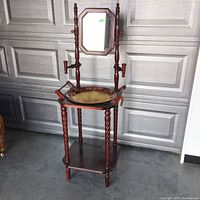 Front view of the vintage wash basin stand showing the brass basin, twisted spindle legs, bottom shelf, and octagonal mirror with wooden supports.