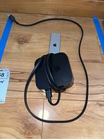 Apple TV device with power cable coiled around it on wooden surface