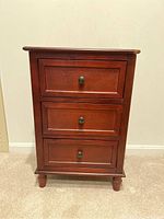 Front view of the wooden chest of drawers showing three drawers and damage on the top right front corner.