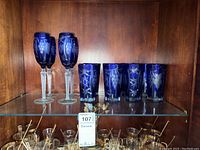 Cobalt blue crystal stemware and tumblers arranged on shelf, showing etch details.