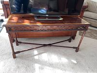 Full view of the wooden console table showing tabletop, carved apron, and leg structure.