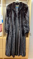 Full-length view of dark mink coat hanging in shelving unit