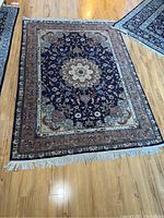 Full view of rug laid flat on hardwood floor showing overall pattern and top fringe