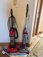 Photo showing two upright vacuum cleaners side by side, Dirt Devil Endurance on the left and Shark Rotator on the right.