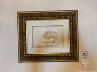 Full view of framed carved flower relief wall art showing ornate gold-toned frame and white mat
