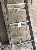 Full view of the aluminum extension ladder extended, showing the middle section, rungs, and yellow rope pulley system.