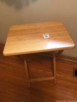 Front view of the wooden folding table showing the rectangular top surface with a light wood finish and rounded corners.