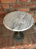 Full view of marble top table showing round marble surface and wrought iron base.