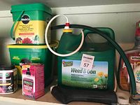 Shelf with multiple gardening items including Miracle-Gro plant food buckets, Weed B Gon container with hose, and assorted fertilizers.