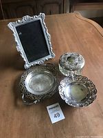 Overview of the set showing all silver trinket dishes and pewter picture frame on wooden table