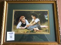 Photo shows the beautifully framed print with an ornate gold frame, green double matting, and a detailed depiction of two young girls outdoors.