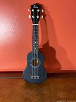 Front view of black Aloha ukulele showing full body, neck and headstock with Aloha logo.