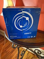 Blue and white cardboard box showing product branding and cable length (500ft) with category and outdoor use indicated