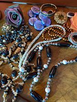 Full lot on surface showing purple rose brooch, purple earrings, star brooch, and various beaded necklaces.