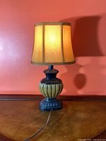 Front view of ceramic table lamp showing black base with greenish-yellow bamboo pattern and beige fabric shade.