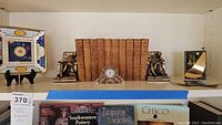 Overall lot view showing plate, bookends, books, clock, and sailboat figurine