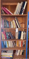 Full wooden bookshelf with assorted hardback and paperback books arranged on five shelves.