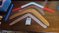 Four boomerangs on a table, showing the overall shape and colors including one with painted red and white ends.
