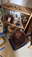 Wooden bowls, wicker basket, round wood trivets on shelves. Various decorative items including a doctor figurine.