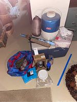 Overall view of camping gear including coolers, water jug, umbrellas, and bag of miscellaneous items.