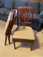 Two wood folding chairs, one folded and one open, showing the front and side views including the upholstered seats and slatted backs.