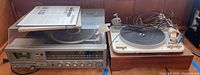 Wide shot showing Garrard turntable with white platter on wooden base next to Sanyo stereo system with clear dust cover and cassette player.