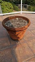 Large clay planter with embossed floral design and soil inside