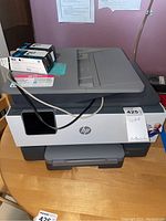 Front and top view of HP OfficeJet Pro 9015 printer with ink cartridges placed on top on a wooden table