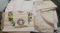 Table linens stacked showing embroidery, lace, and embossed elements
