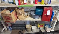 Shelf with cardboard boxes, stoneware crocks, tool boxes, a colander, and household items