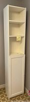 Full front view of the white tall narrow cabinet showing three open shelves and closed bottom door.