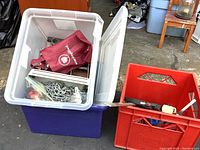 Open plastic totes with metal chain, grommets, and other hardware inside.