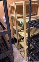 Photo showing two beige metal shelves stacked beside black plastic shelves in a basement storage area.