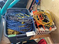 Tote with blue climbing rope, yellow synthetic rope, and white rope, also extension cords and work lamp in a separate white basket