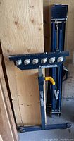 Mastercraft table extender leaning against plywood wall with two folded metal sawhorses behind