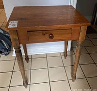 Front view with drawer closed showing turned legs and drawer front.